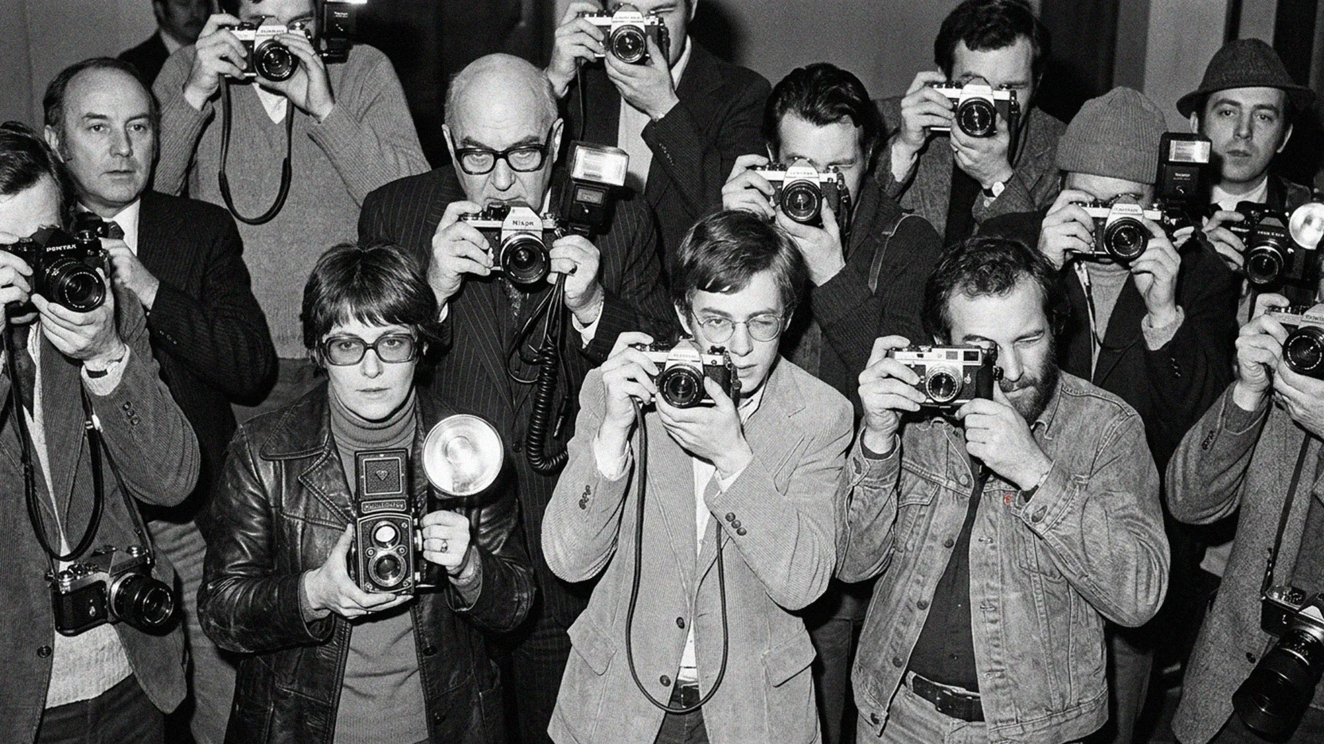 A group of photographers raising their cameras