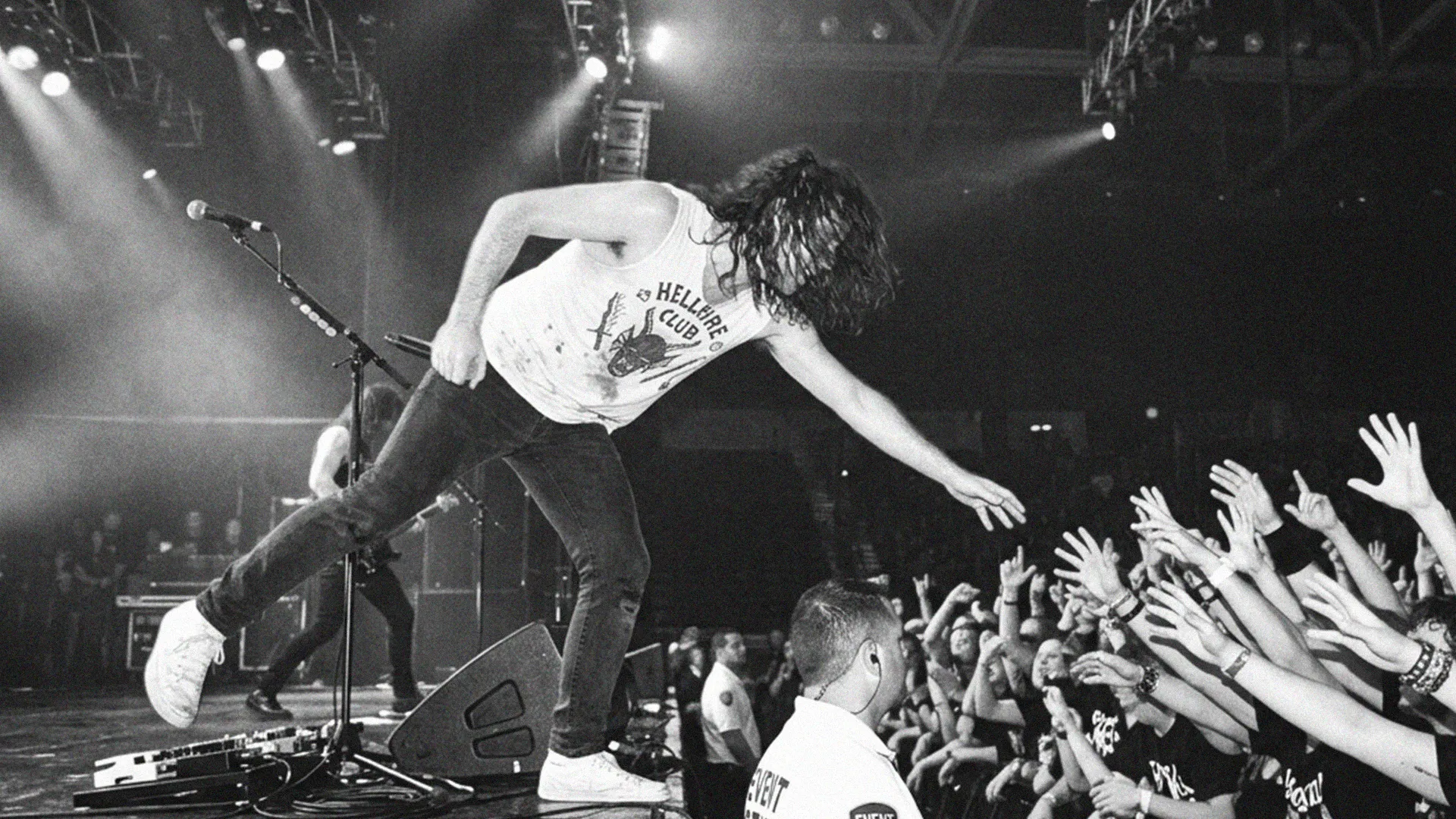 A singer reaching towards the outstretched hands of a concert audience